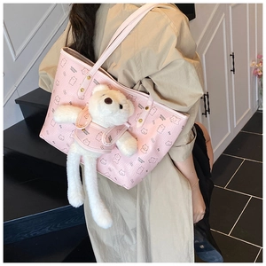 Pink tote bag with bear patterns and plush bear charm shown in a lifestyle indoor setting