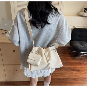 Detail of minimalist cream white drawstring bucket bag with silver metal ring and mini pouch