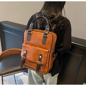 Vintage brown leather backpack with buckle straps and top handle shown on a model