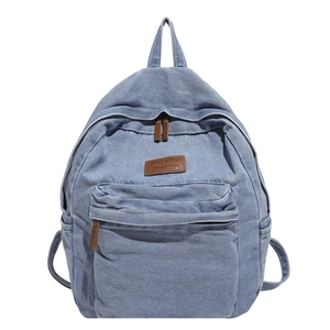 Vintage light blue denim backpack with brown leather accents and front pocket on white background