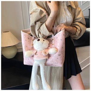 Close-up of pink leather tote bag with cartoon bear pattern and plush bear charm accessory