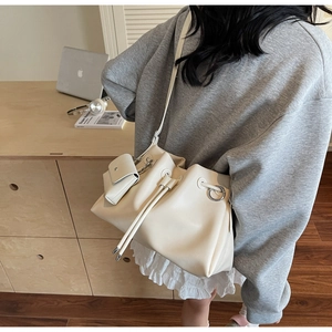 Detail view of cream drawstring bucket bag with silver rings and mini pouch charm