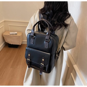 British style black PU leather backpack with brown straps shown on a model's back