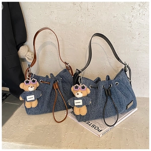 Detail of denim bucket bags with drawstring closure and cute teddy bear keychain charms