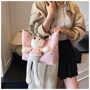 Close-up of pink leather tote bag featuring a cute white plush bear charm and bear patterns