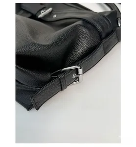 Detail of silver metal buckle and litchi grain leather on black tote bag