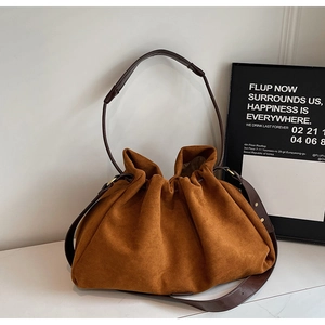 Close-up of brown suede bucket bag texture with leather shoulder strap and buckle