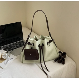Detail of mint green bucket bag featuring drawstring closure and small square charm pendant