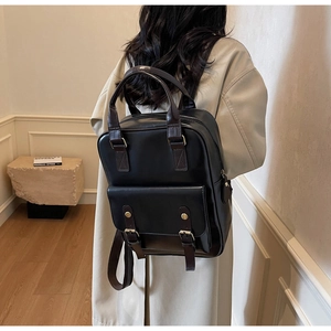 Detail view of stylish vintage black leather backpack with dark brown straps worn by model