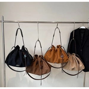 Showcase of four suede drawstring bucket bags in neutral tones hanging on silver racks