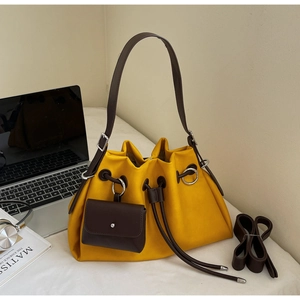 Detail of yellow and brown drawstring bucket bag with mini pouch on a modern desk