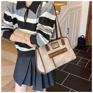 Detail showing distressed texture and contrast leather trim on a beige shoulder bag