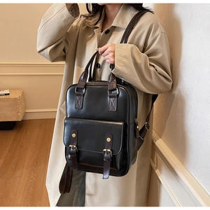 Detail view of retro brown leather backpack featuring brass buckles and top handle