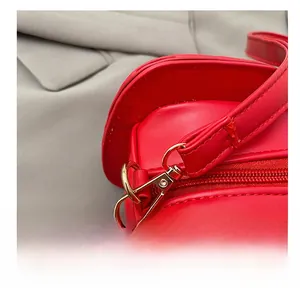 Détail du crochet en métal doré et de la fermeture éclair du sac bandoulière rouge