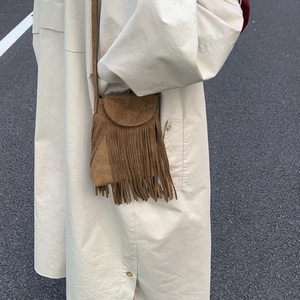 Minimalist brown suede tassel handbag worn by model in trench coat outdoors