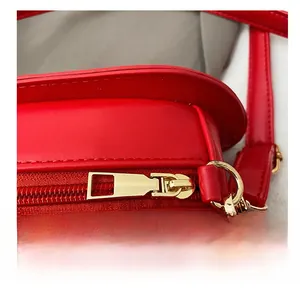 Détail de la fermeture éclair en métal doré lisse sur un sac à bandoulière rouge