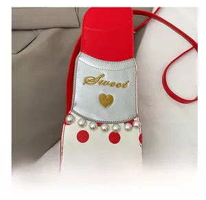 Gros plan du sac à bandoulière en forme de rouge à lèvres avec pois et perles