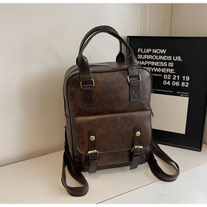 Detail of dark brown faux leather backpack showing vintage texture and flap buckles