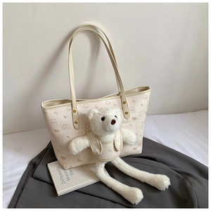 Close-up of cream leather tote bag with cute bear print and plush bear doll charm