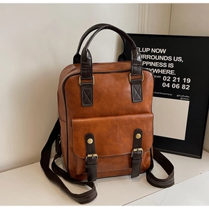 Detail view of the brown retro faux leather backpack showing handles and adjustable straps