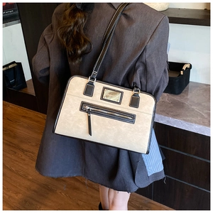 Detail of cream shoulder tote bag with black contrast stitching and front zipper pocket