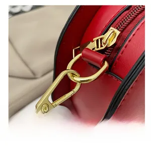 Macro shot of durable gold-tone metal hook and zipper hardware on red PU leather bag