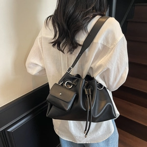 Minimalist black leather drawstring bucket bag with silver hardware on model back