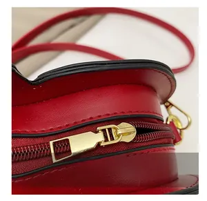 Close-up of smooth gold metal zipper and red faux leather texture on maple leaf bag