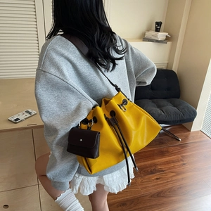 Minimalist yellow drawstring bucket bag with contrast brown pouch and long shoulder strap