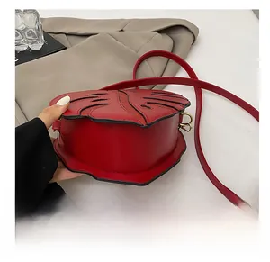 Detail showing red heart-leaf crossbody bag with embossed leaf texture and gold hardware