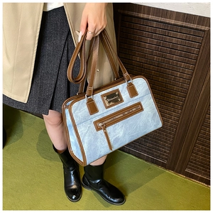 Detail of the blue denim texture and brown leather trim on the stylish shoulder bag