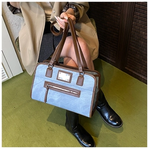Detail of vintage blue tote bag with brown leather trim and metallic zipper accents