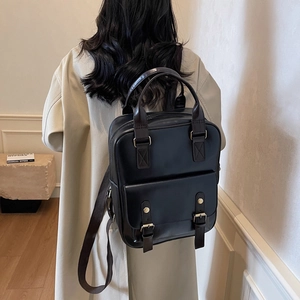 Minimalist black leather square backpack with dual buckle straps and top handle for women