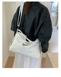 Detail view of white lychee textured tote bag with metal buckle and long shoulder strap