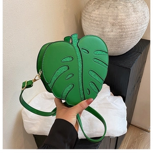 Detail of green monstera leaf bag featuring glitter accents and PU leather texture