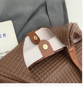 Detailed shot of brown woven tote bag featuring interior gold magnetic snap closure