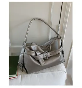 Close-up of silver tote bag with decorative buckle and pebble texture on white sofa