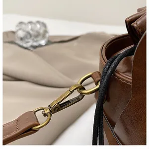 Macro shot of retro bronze hook and D-ring on dark brown leather shoulder strap