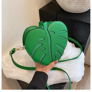 Close-up of green leaf-shaped handbag with sequin veins and gold metal hardware