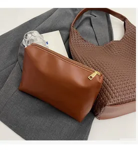 Detail of smooth metal zipper and textured dark brown leather on stylish toiletry bag