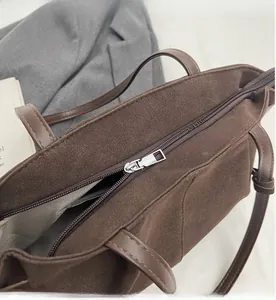 Detail view of the smooth metal zipper and gray lining of the brown suede tote bag