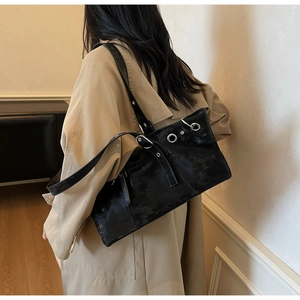 Detail of a vintage black leather shoulder bag with silver eyelets and buckle accents