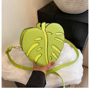 Detail of lime green monstera leaf shaped crossbody bag with hollowed veins and gold hardware
