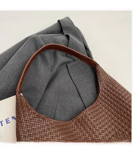 Close-up of tight woven leather texture and smooth brown handle on a tote bag