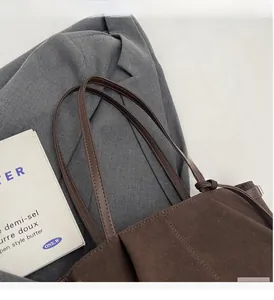 Detail of dark coffee suede tote bag featuring slim brown straps and ruched fabric texture