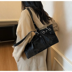 Detail of vintage black leather shoulder bag with silver eyelets and punk style buckles