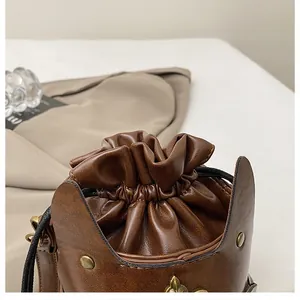 Detail of vintage brown leather bucket bag with gold studs and drawstring closure