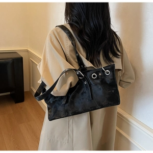 Detail of vintage punk black shoulder bag with silver metal eyelets on model's shoulder