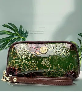 Close-up of floral embossed wristlet with green glossy leather and golden metal clasp