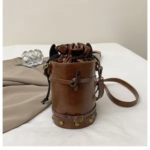 Detail of dark brown leather bucket bag with drawstring closure and bronze rivets